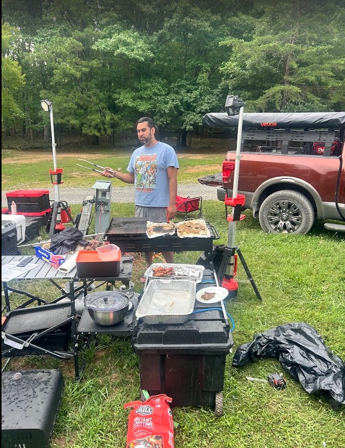 Cast iron pans of food cooking over a camp stove at the campsite