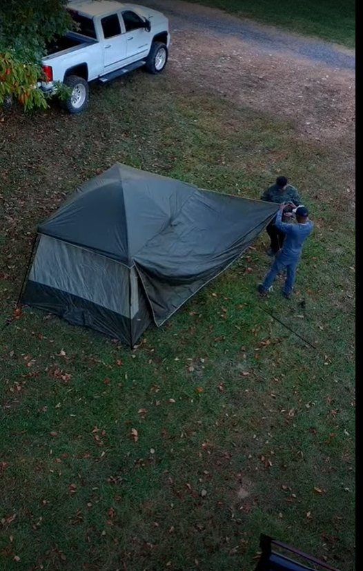 A large, fully set up family tent at a wooded campsite